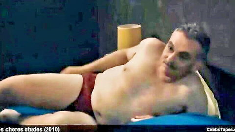 Chubby middle-aged man lounging shirtless in tight red speedo with bulge on blue bed