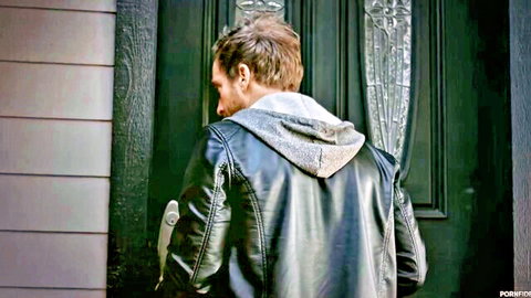 Man in black leather jacket with hoodie stands at green door from behind