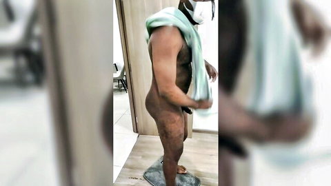 Nude muscular black man standing with towel, post-shower pose