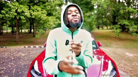 Black man in green hoodie posing by red sports car for Blind Date adult video