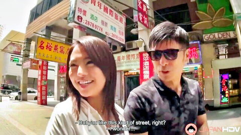 Smiling Japanese couple on neon-lit street in casual clothes teasing public encounter