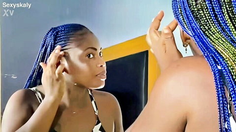 Ebony babe with blue braids poses seductively showing deep cleavage in white bikini top