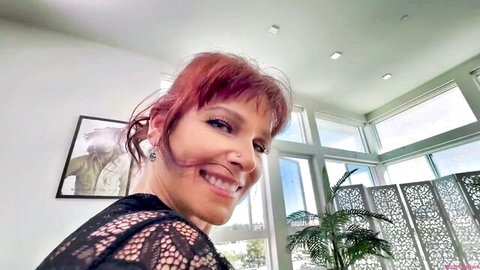 Smiling redhead MILF in sheer black lace top teasing seductively