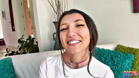 Maya Woulfe smiling playfully in white top and pink collar