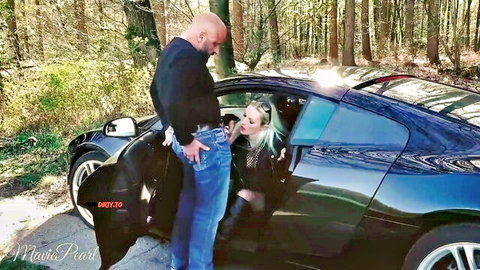 Bald man pulls out thick cock for hot blonde in open black Porsche outdoors in forest