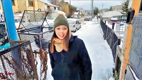 Playful brunette teen smiling with tongue out on snowy winter street