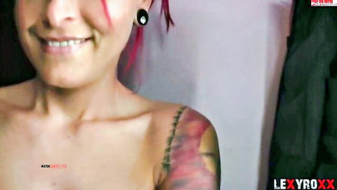 LexyRoxx smiling topless redhead with shoulder tattoos