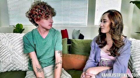 Tattooed curly-haired teen guy sits intimately with long-haired brunette in purple hoodie on couch in taboo FamilyStrokes scene