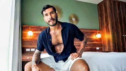 Muscular Latino stud Jeus in open shirt, teasing on bed