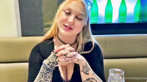 Tattooed blonde babe with huge tits in deep cleavage teases seductively on couch