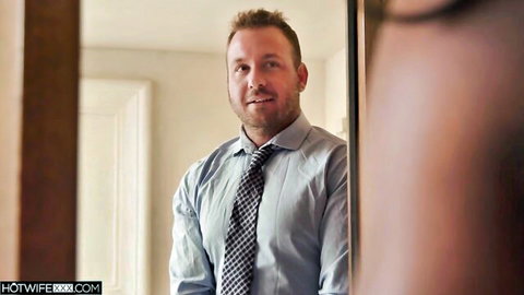 Handsome bearded man in blue shirt and tie smiling confidently in bedroom mirror