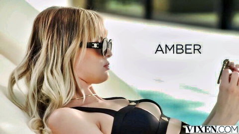 Blonde babe Amber lounging poolside in skimpy black bikini top flaunting deep cleavage and perky tits
