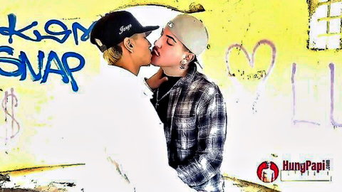 Two hot gay guys passionately kissing against graffiti wall wearing caps