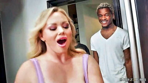 Busty blonde MILF in purple top opens mouth wide with big tits heaving as black stud grins behind her