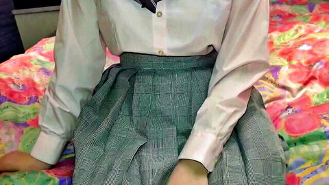 Japanese schoolgirl in white shirt and plaid skirt sits on bed spreading legs teasing