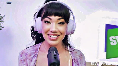 Sexy Asian streamer with bangs smiling into mic wearing white headphones and sheer top