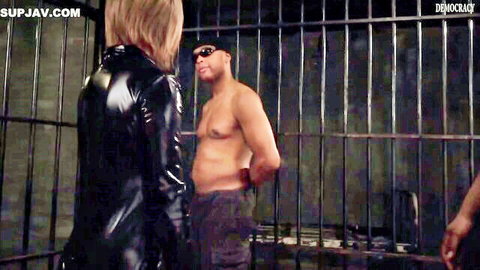 Blonde in latex dress teases cuffed shirtless black man behind jail bars