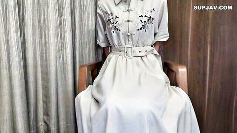 Sexy Asian woman in elegant gray embroidered dress sits with legs spread teasing on wooden chair