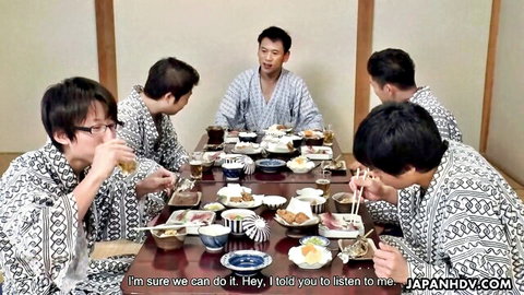 Group of Japanese men in yukatas eating sushi and rice at low dinner table