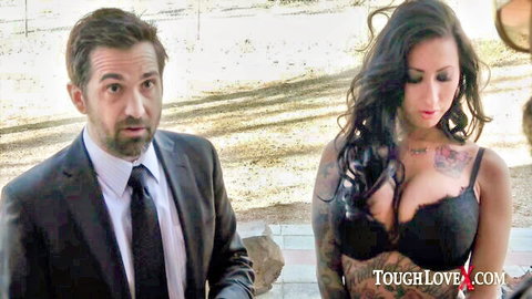 Tattooed brunette with big tits spilling from black lace bra next to suited man outdoors