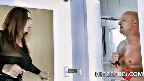 Surprised brunette in sheer black top shocked by muscular bald guy peeking shirtless from bathroom door