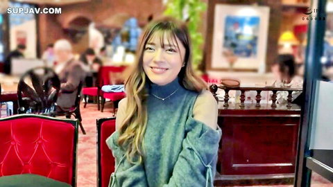 Cute Japanese woman smiling seductively in off-shoulder sweater teasing in restaurant