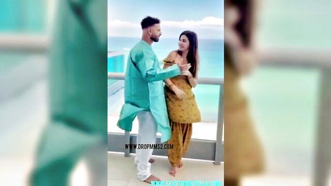 Punjabi NRI girl in yellow salwar kameez with boyfriend in blue kurta on beach balcony