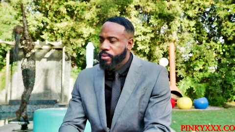 Ebony man in gray suit and tie sits on turquoise stool in colorful playground