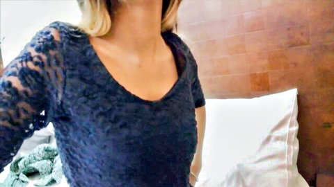 Sexy blonde in sheer navy lace top teasing deep cleavage on bed