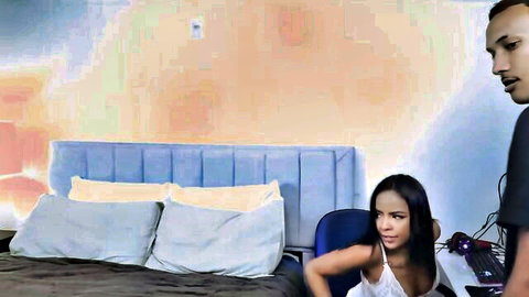 Ebony woman in white tank top leaning back as black man watches intently