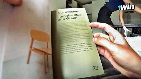 Gloved hand holding open book page 'Our mission: Turn the Blue into Green' with wooden chair and 1win logo