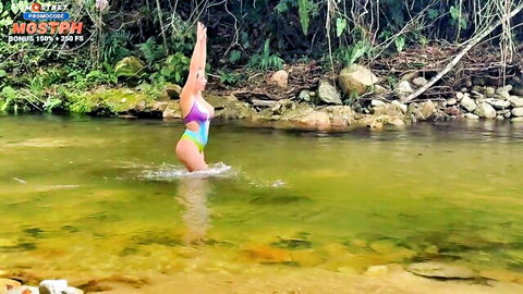 Sensual fit babe in colorful bikini posing arms raised in jungle river water