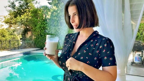 Curvy brunette with big tits in floral dress holding milk glass poolside