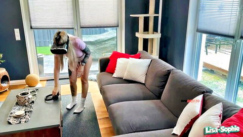 Tattooed blonde in VR headset bends over couch showing juicy ass in tight shorts