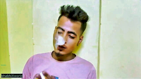 Handsome Indian man exhaling smoke in pink t-shirt after office hookup