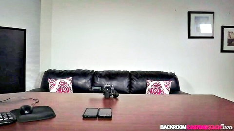Empty Backroom Casting Couch room with black leather couch, pink pillows, desk, phones and camera setup