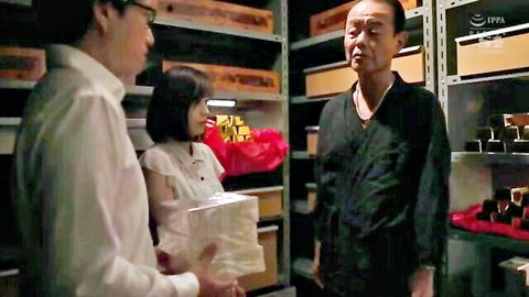 Young Asian woman in frilly blouse holding white cloth with two suited men in storage room