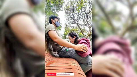 Amateur Indonesian couple cuddling intimately on public park bench outdoors