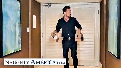 Handsome delivery man in black shirt holds two bags outside hotel room door ready for wife cheating fuck.