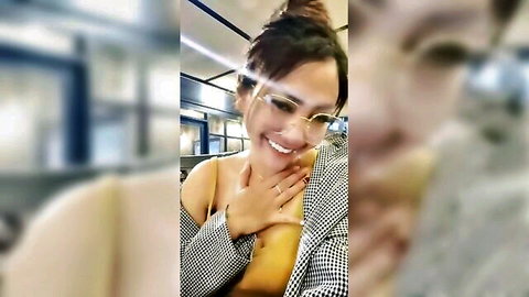 Petite smiling Asian woman in off-shoulder yellow top and checkered jacket on train