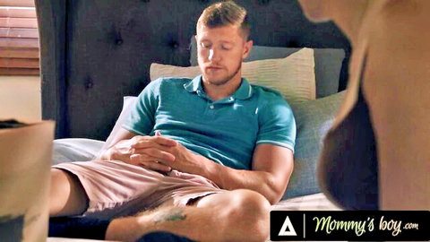 Muscular stepson in shorts lounges on bed watching busty MILF stepmom's bare ass and side tits