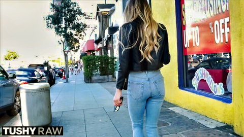 Naomi Swann in tight jeans and leather jacket, teasing ass on sunny urban street
