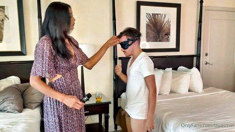Yasmin in flowery dress dominating blindfolded man in underwear