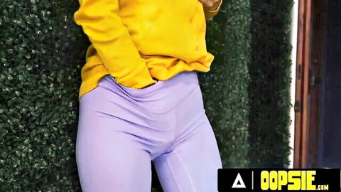 Trans woman in yellow sweater and tight purple pants showing cameltoe
