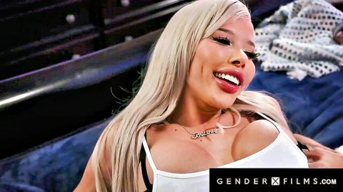 Brittney Kade blonde trans babe smiling seductively in low-cut white top, big cleavage