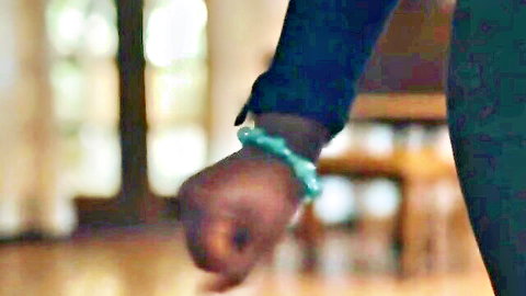 Osa Lovely's dark-skinned wrist with green bracelet, clenched fist close-up