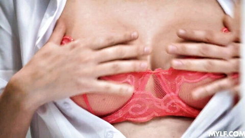 Slender MILF teases in red lace bra, hands cupping breasts
