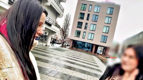 Two long-haired brunettes in fur coats smiling on urban striped pavement street