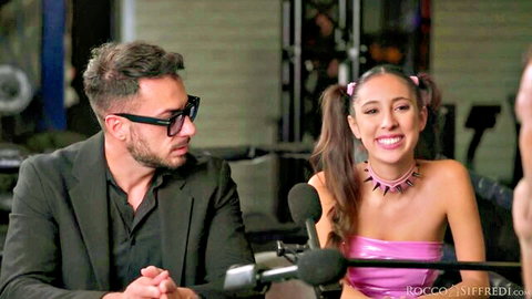 Eva Generosi smiles on Rocco's Sex Podcast in pink top and choker
