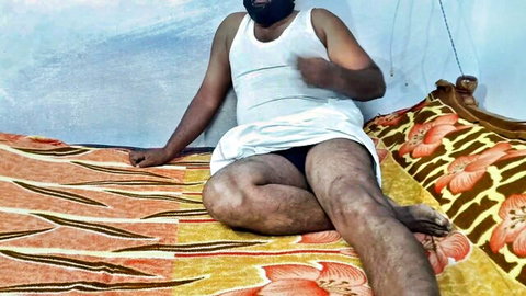 Hairy Indian man in white tank top and underwear sitting with legs spread